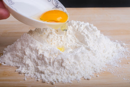 Pouring an egg onto the flourの写真素材