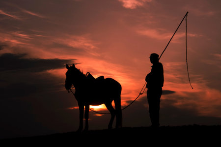 Silhouette of horse and herdsmanの写真素材