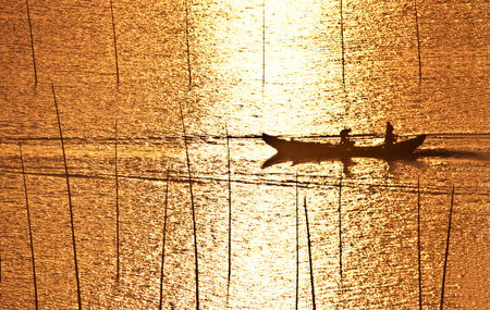 Silhouette of fishermen on the boat during sunsetの写真素材