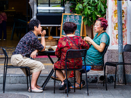 HAIKOU, HAINAN, CHINA â 2 MAR 2019 â Middle-aged Chinese women socialize outside a cafe. China has a rapidly aging population.のeditorial素材