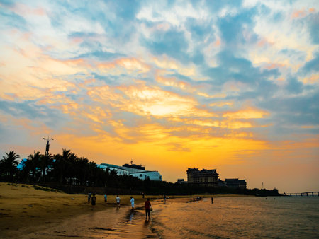 Tourists enjoy the beach at Sanya, Hainan, China during a beautiful golden sunsetの写真素材