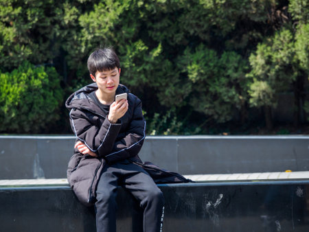 SHANGHAI, CHINA - 12 MAR 2019 - A young Asian Chinese man in casual dress on his vivo smartphone in downtown Shanghai. With copy space. Connected / communication conceptのeditorial素材