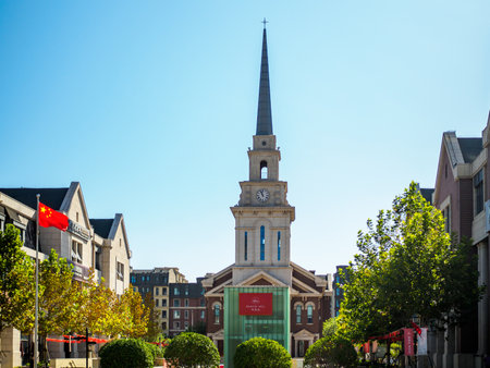 TIANJIN, CHINA â 5 OCT 2019 â Beacon Hill, an upmarket residential housing development built in a traditional European style with a steepled church and European style houses. Chinese / China National flag in the foreground.のeditorial素材