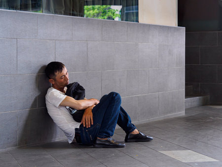 SINGAPORE - 5 APR 2019 - Tired exhausted Asian Chinese man napping / sleeping on the sidewalk in downtown Singapore during lunch hourのeditorial素材