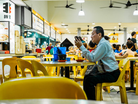 SINGAPORE - 17 MAR 2019 - A middle aged Asian Chinese Singaporean man in office attire enjoys a late night beer at an eatery / coffeeshop / kopitiam, / hawker centreのeditorial素材