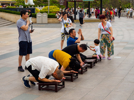 NANSHAN CULTURAL PARK, HAINAN, CHINA - 5 MAR 2019 â Asian Chinese Buddhist devotees kneel and kowtow / bow in prayer to the Goddess of Mercy, Guanyin at Nanshan Templeのeditorial素材