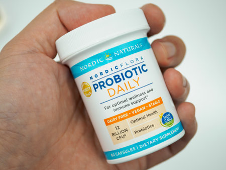 Close up of hand holding a bottle of Nordic Flora brand probiotics pills isolated on a white backgroundのeditorial素材