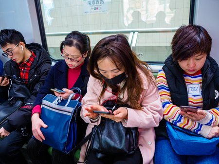 SHANGHAI, CHINA - 12 MAR 2019 - a row of commuters on the Shanghai Metro all on their smartphones. China has an extremely high rate of smartphone market penetrationのeditorial素材
