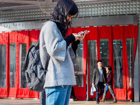 SHANGHAI, CHINA - 12 MAR 2019 - An attractive young Asian Chinese woman on her smartphone outside a shopping mall in downtown Shanghai. Connected / communication conceptのeditorial素材