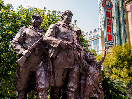 Statue of the People Liberation Army (PLA) at Nanjing Road, Shanghai, with the New World Emporium mall in the background â a juxtaposition of communism and capitalismのeditorial素材