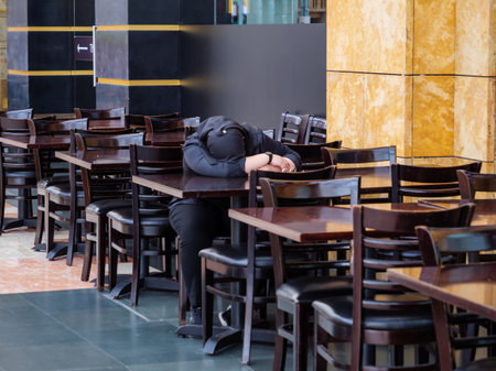 SINGAPORE â 12 MAR 2020 â A woman wearing a hijab takes a nap at the empty tables of the closed Hard Rock Cafe restaurant on Sentosa Island, Singapore. Business has dropped due to covid-19 / coronavirus concernsのeditorial素材