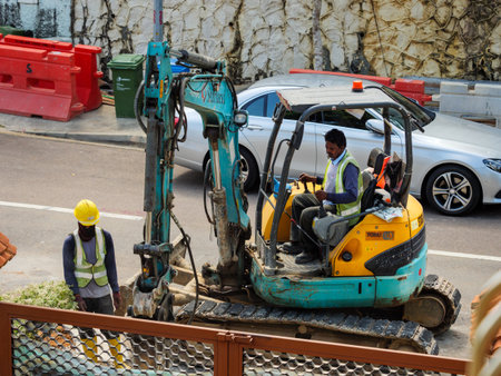SINGAPORE â€“ 28 FEB 2020 - Indian / Bangladeshi  construction workers use a digger to perform...