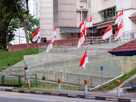 SINGAPORE â JUL 31, 2020 â A man walks past a row of Singaporean national flags placed at Sin Ming HDB residential estate in preparation for National Dayのeditorial素材