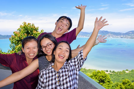 Family of tourists smiling are happy and show their hands invite to see the beautiful landscape of sea on Khao-Khad mountain viewpoint famous attractions in Phuket Province, Thailandの写真素材