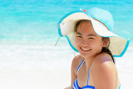 Girl in a blue swimwear sitting a happy on the beach with the sea as background during summer at Koh Miang Island, Mu Ko Similan National Park, Phang Nga province, Thailandの写真素材