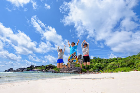 Family jumping on beach near the sea under blue sky and clouds of summer at Koh Similan Island in Mu Ko Similan National Park, Phang Nga province, Thailandの写真素材