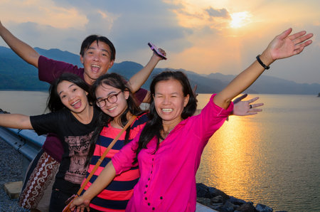 Group of people the family asian tourists are happy during the sunset over the lake at Khuean Sinakharin Dam in Kanchanaburi Province, Thailandの写真素材