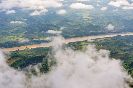 High angle view of Mekong River is the border between Thailand and Laos and farmland along the river looking through the clouds from Doi Pha Tang view point in Chiang Rai Province, Thailandの写真素材