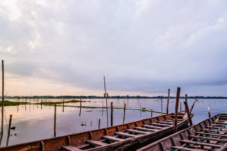 Old wooden boat floating on the water amidst the natural landscape of the morning at Kwan Phayao Lake in Phayao Province, Thailandの写真素材