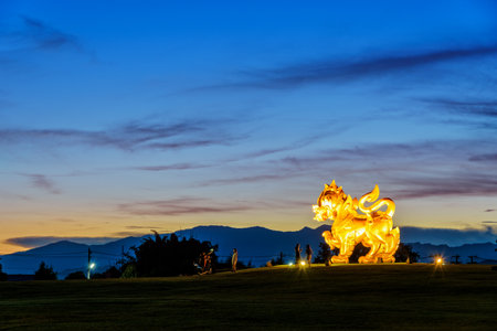 CHIANG RAI, THAILAND-OCT. 27 2016: Gold Singha statue at Singha Park is the symbol of Boon Rawd Farm surrounded by the spotlight during the twilight on blue sky background, famous tourist destination, OCT. 27 2016 in Thailandのeditorial素材