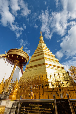 Wat Phra That Cho Hae Buddhism Temple with golden pagoda on blue sky background. Places worship of buddhists and attractions famous religion at Phrae Province, Thailandの写真素材