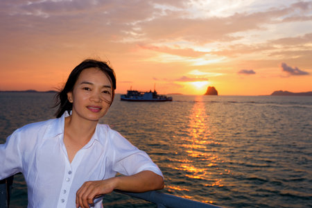 Beautiful nature of colorful sky and sun at sunset over the sea, women tourist on the deck of a large passenger boat while cruising to Koh Samui Island in Surat Thani province, Thailandの写真素材
