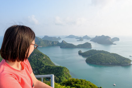 Woman tourist on the balcony is peak view point of Ko Wua Ta Lap island looking beautiful nature landscape during sunrise over the sea in Mu Ko Ang Thong National Park, Surat Thani, Thailandの写真素材