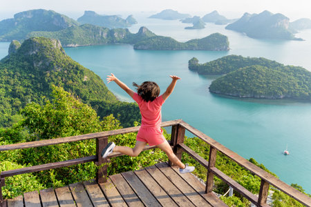 Woman tourist jumping with happy it has reached the peak mountain to see the beautiful natural landscape of sea from view point of Ko Wua Ta Lap island in Mu Ko Ang Thong, Surat Thani, Thailandの写真素材