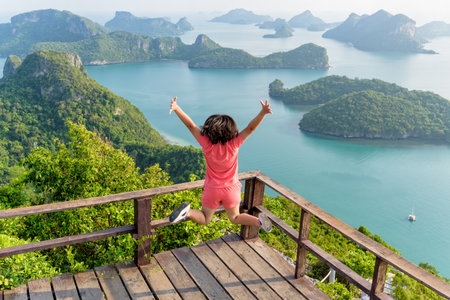 Woman tourist jumping with happy it has reached the peak mountain to see the beautiful natural landscape of sea from view point of Ko Wua Ta Lap island in Mu Ko Ang Thong, Surat Thani, Thailandの写真素材