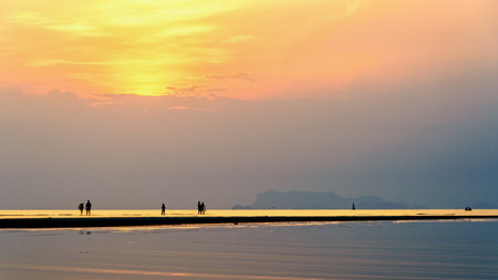Silhouette of people relaxing on the beach watching the beautiful natural landscape colorful sky and sea during a sunset at Nathon Sunset Viewpoint in Ko Samui, Surat Thani, Thailand, 16:9 widescreenの写真素材