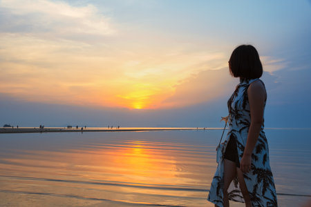 Young woman are standing watching the beautiful natural landscape, colorful of the sky and the sea during a sunset on the beach at Nathon Sunset Viewpoint in Ko Samui island, Surat Thani, Thailandの写真素材