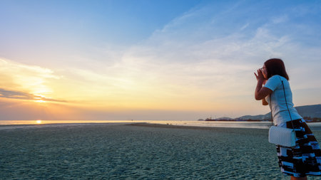 Happy women tourist raise hands at the mouth yelling and beautiful natural landscape of colorful sky and sea during a sunset at Nathon Sunset Viewpoint in Samui island, Surat Thani, Thailand, 16:9 widescreenの写真素材