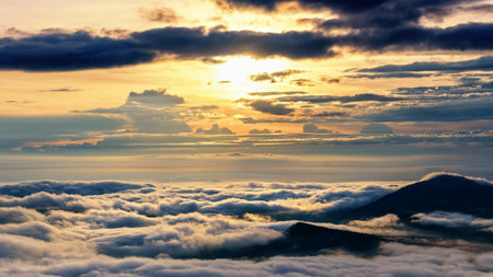 Beautiful nature landscape the sun is above the sea fog that covers the mountains and bright sky during sunrise in the winter at viewpoint of Phu Ruea National Park, Loei province, Thailand.の写真素材