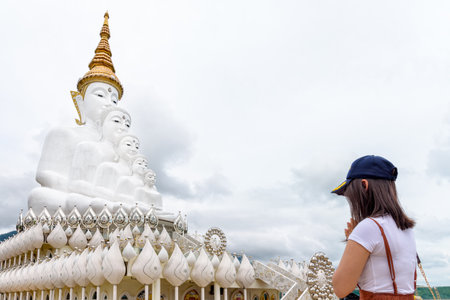 Woman standing worship respect praying for blessing with Buddha statue has large white five body at Wat Phra That Pha Sorn Kaew Temple is a famous tourist attractions in Khao Kho, Phetchabun, Thailandの写真素材