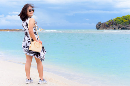 Beautiful nature landscape and cute teen girl tourist wearing sunglasse shoulder bag fashion smiling with happy on the beach and sea in summer at Tarutao island, Satun, Thailandの写真素材