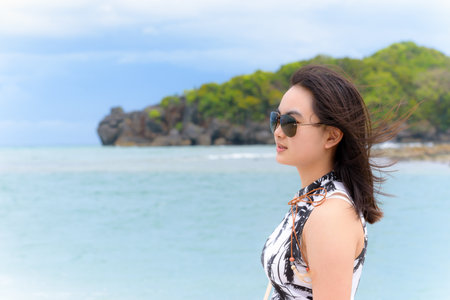 Beautiful woman tourist wearing sunglasse smiling looking at the nature landscape of the beach and the sea in summer sky on Tarutao island National Park, Satun, Thailandの写真素材