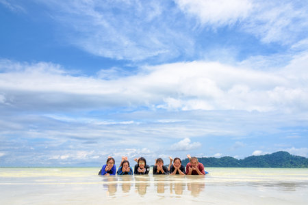 Asian people group adult and teens are family, Happy life enjoy by lying together on the beach on blue sky background, vacation in summer holiday at Ko Lipe and Ra Wi island, Tarutao, Thailandの写真素材