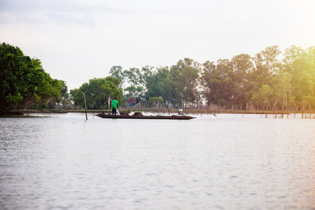 Native fisherman are standing prepare the nets to catch fish, on a small wooden boat under the morning light, Lifestyle in the countryside at Pakpra canal, Songkhla Lake, Phatthalung, Thailandの写真素材