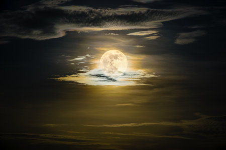 Super full moon on the yellow sky at midnight, golden moonlight reflect the cloud, Beautiful nature landscape view at night scene for backgroundの写真素材