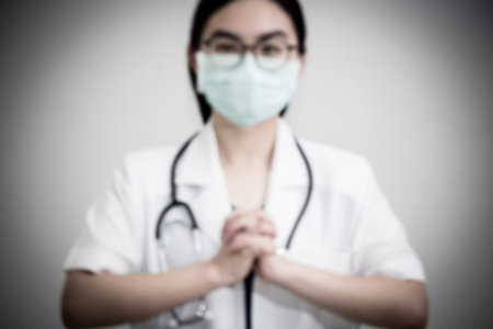 Blur for background Asian woman doctor wear mask hand clasp gesture of begging for help, Let's cooperate, work together, confederate, help each other to stop the epidemic of the Corona Virus conceptの写真素材