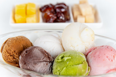 Closeup side view multi colored ice cream in a clear dish and sweet processed fruit for eating together in Thai style, Set of colorful ice cream scoops of different colors on the white table backgroundの写真素材