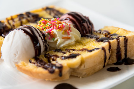 Closeup side view Honey Toast bread and Chocolate brown Ice cream scoop topped with chocolate syrup decorate with a chocolate tablet in a white plate on the table sweet cool dessert in summerの写真素材