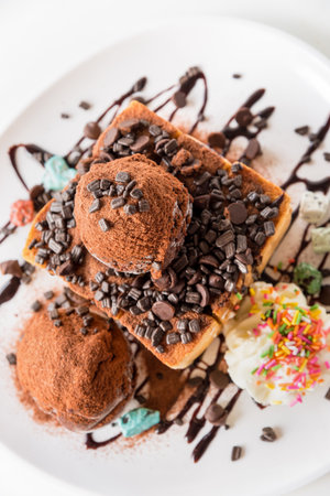 Closeup top view Honey Toast bread and Chocolate brown Ice cream scoop topped with syrup decorate with chocolate tablet in a white plate on the table sweet cool snack in summerの写真素材
