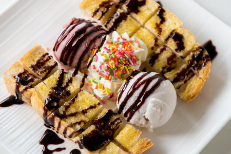 Closeup top view Honey Toast bread served vanilla coconut milk ice cream scoop with chocolate syrup decorate and cream sugar topping sprinkle in a white plate on the table sweet cool dessert in summerの写真素材