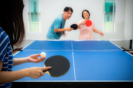 Couple fun playing table tennis   indoor together leisure with competing in sports games at house. Father mother and daughter Asian family enjoy recreation exercise stay at home in Thailandの写真素材