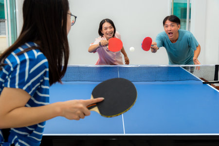 Couple fun playing table tennis   indoor together leisure with competing in sports games at house. Father mother and daughter Asian family enjoy recreation exercise stay at home in Thailandの写真素材