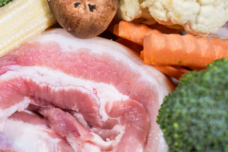 Close up piece fresh raw meat of pork belly and many vegetables are baby corn, broccoli flowers, mushroom, carrot, cauliflower Ingredients for food preparation cookingの写真素材