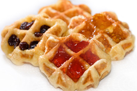 Close up many fresh waffles with above strawberry jam, pineapple jam, and dried raisins isolated on white background. Making homemade food or dessert at homeの写真素材