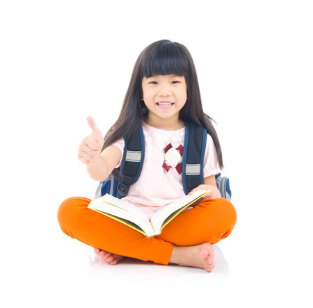 Asian girl sitting on the floor and reading. Isolated on white background.の写真素材