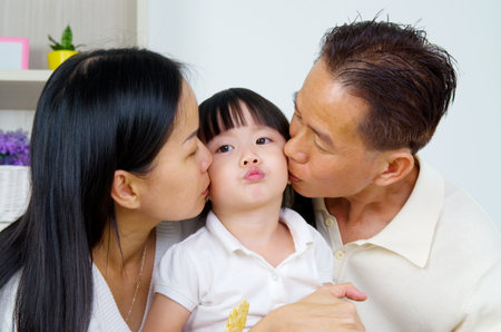 asian parent kissing their baby girlの写真素材